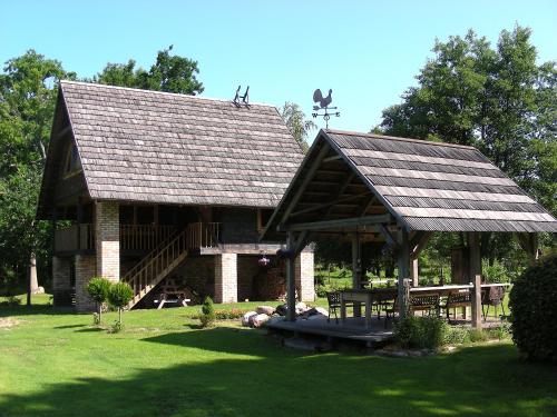 a large building with a roof on a grass field at Griķi in Kalnišķi