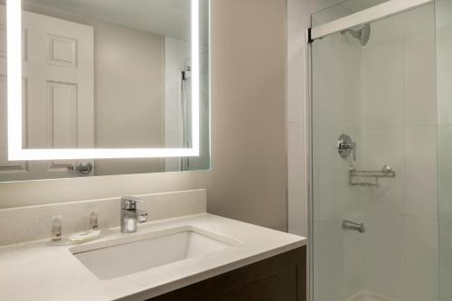a white bathroom with a sink and a shower at Days Inn by Wyndham Toronto West Mississauga in Mississauga