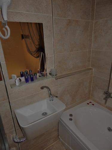 a bathroom with a sink and a tub and a mirror at Gödence Hotel Restoran Bungalow in Gödence