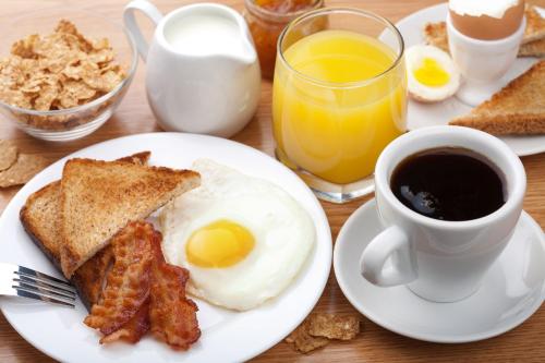 a breakfast plate with eggs bacon and toast and a cup of coffee at Hotel Del Mar Inn in Barranquilla