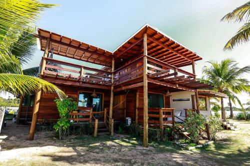 a wooden house on the beach with palm trees at Pôr do Sol Eco Suítes in Barra Grande