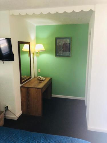 a room with a vanity with a mirror and a television at Woodridge Motel in Terre Haute