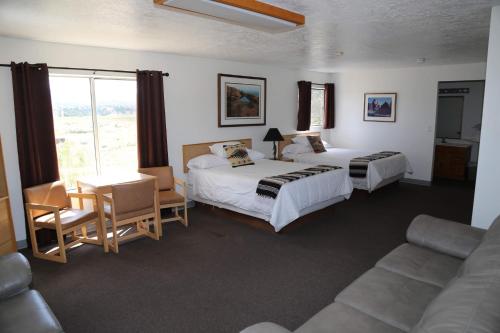 哈奇的住宿－The Riverside Ranch Motel and RV Park Southern Utah，酒店客房带两张床、一张桌子和一张沙发