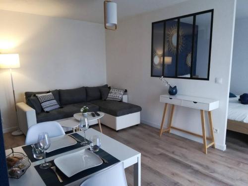 ein Wohnzimmer mit einem Sofa und einem Tisch in der Unterkunft Appartement Cosy proche Météo France et Airbus in Toulouse