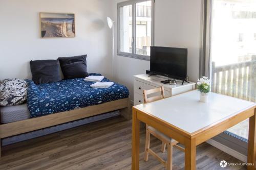 a small room with a bed and a table and a television at Studio moderne accès plage, piscine et tennis in Cabourg