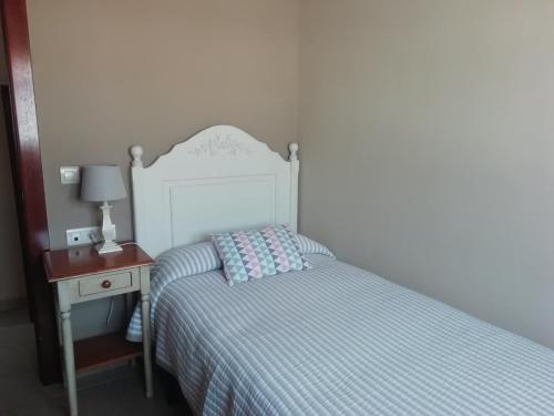 ein kleines Schlafzimmer mit einem Bett und einem Nachttisch mit einem Bett sidx sidx sidx in der Unterkunft Apartamentos la Marina in Ribadesella