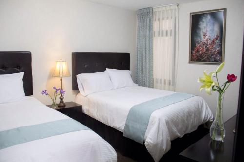 a hotel room with two beds and a vase of flowers at Hotel Nube Nueve in Chignahuapan