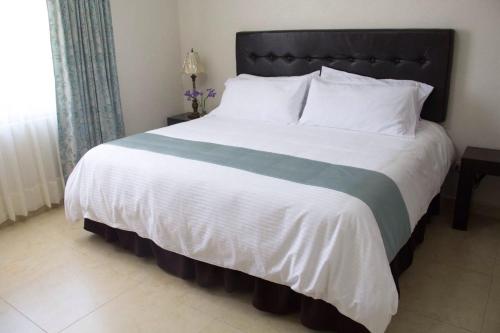 a large bed with a green and white blanket at Hotel Nube Nueve in Chignahuapan