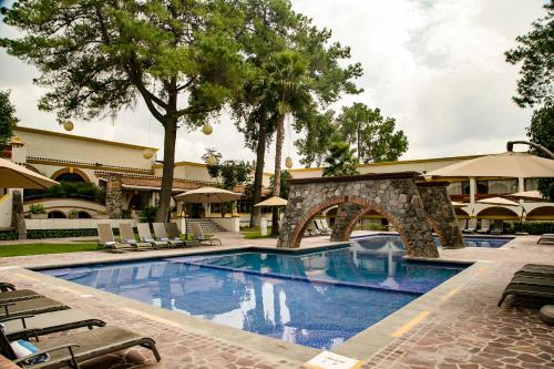 a pool at a hotel with chairs and trees at Imperio De Angeles in San Miguel de Allende