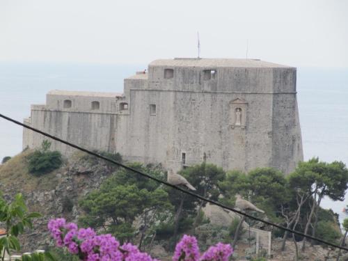 a castle on top of a hill with pink flowers at Room & Apartment Saint John in Dubrovnik