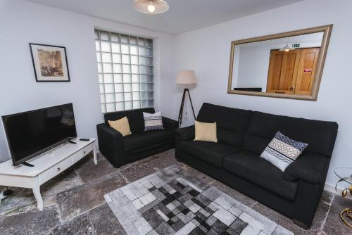 a living room with a black couch and a flat screen tv at Fortaleza do Pico Apartment in Funchal