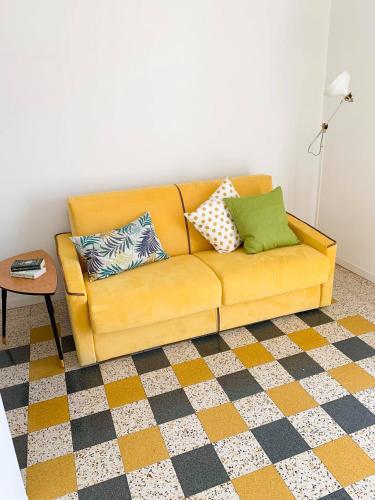 a yellow couch with pillows on it in a living room at La casetta di nonno Vittorio in Albissola Marina