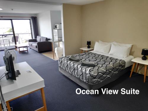 a hotel room with a bed and a living room at Beach House Mollymook in Mollymook