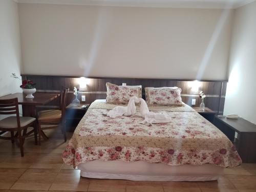 a bedroom with a bed with two towels on it at Grand Enio Hotel e Cantina in Varginha