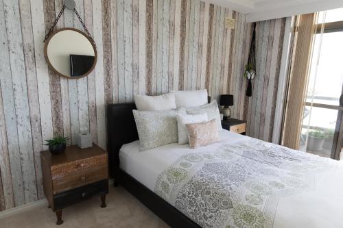 a bedroom with a bed with pillows and a mirror at Beauty at the Beach - modern beachfront apartment in Port Macquarie