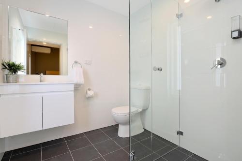 a bathroom with a toilet and a glass shower at Kingsgrove Hotel in Sydney