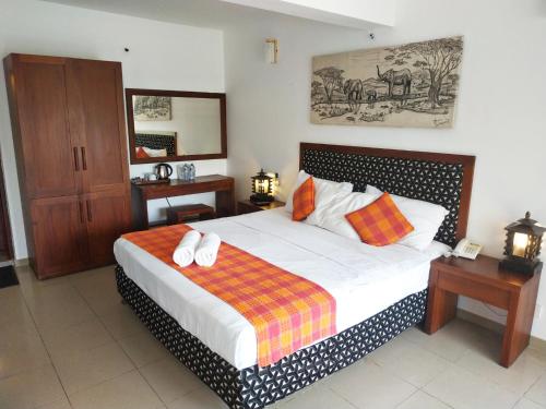 a bedroom with a bed with white sheets and orange pillows at Hotel Pinnalanda in Pinnawala