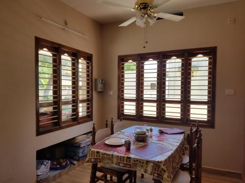 een eetkamer met een tafel en twee ramen bij Elim Vacation Villa in Tarangambādi