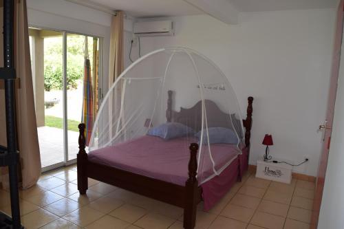 a bed with a canopy in a room at Appartement vue mer in Le Carbet