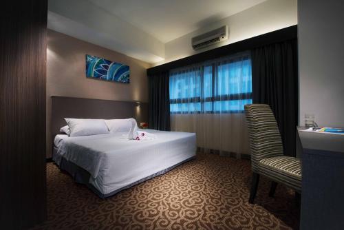 a hotel room with a bed, chair, and nightstand at Crown Regency Serviced Suites in Kuala Lumpur