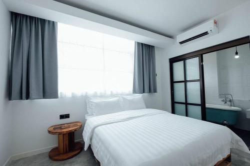 a bedroom with a white bed and a large window at White Loft Hotel in Melaka