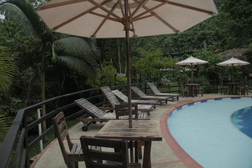 a group of chairs and an umbrella next to a pool at HOTEL LA SELVA Reserva in La Vega