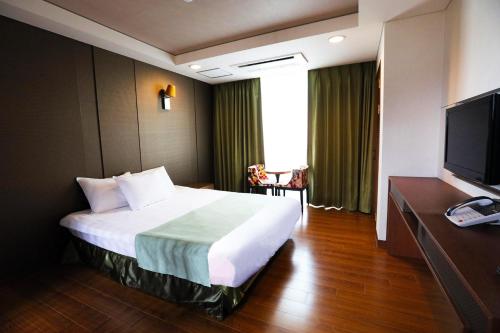 a hotel room with a bed and a flat screen tv at Sobaeksan Punggi Spa Resort in Yeongju
