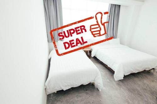 two beds in a room with a super deal sign at White Loft Hotel in Melaka