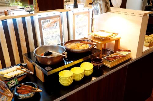a buffet with some food on a counter with dishes at Hotel Hokke Club Niigata Nagaoka in Nagaoka