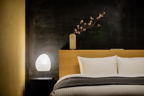 a bedroom with a bed with a vase on top of it at Nazuna Kyoto Gosho in Kyoto
