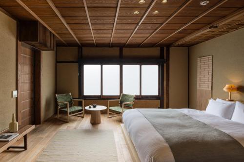 a bedroom with a bed and two chairs and a table at Nazuna Kyoto Gosho in Kyoto