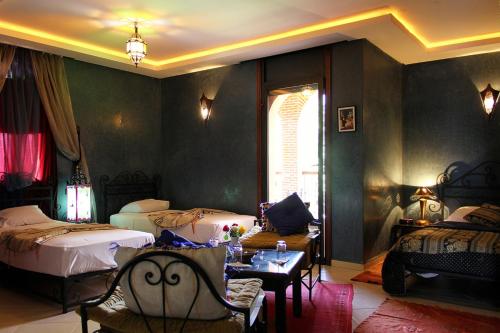 a bedroom with two beds and a table and chairs at Palais Dar Ouladna in Marrakech