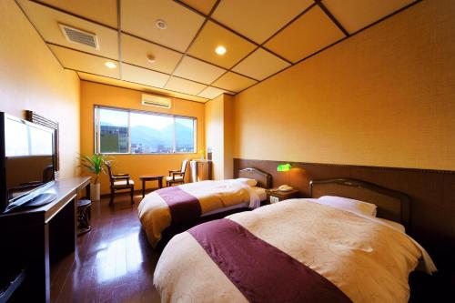 a hotel room with two beds and a flat screen tv at Tenku Yubo Seikaiso in Beppu