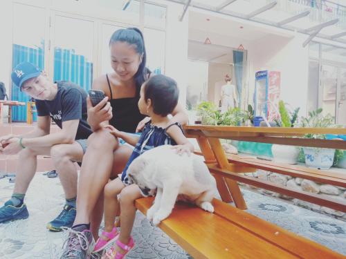a woman sitting on a bench with a child and a dog at Hugo Homestay in Phong Nha