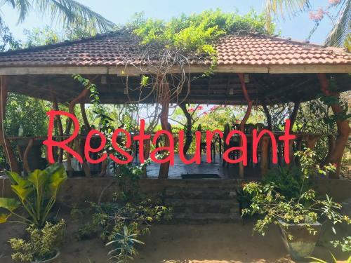 a sign that reads restaurant in front of a gazebo at Temple Flower Guest in Kirinda