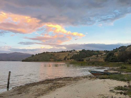 a boat sitting on the shore of a body of water at El Arca de Noah in Tota