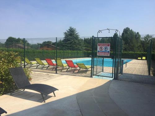 une clôture avec des chaises en face d'une piscine dans l'établissement Le Chalet du Lac - Domaine de la Goujonne, à Saint-Sauveur-lès-Bray