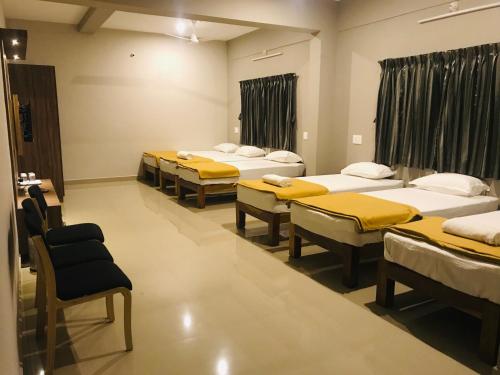 a row of beds in a room with yellow sheets at Sharada Residency in Somvārpet