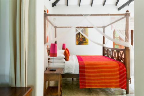 a bedroom with a bed with a red and orange blanket at Rosyth Estate House in Pinnawala