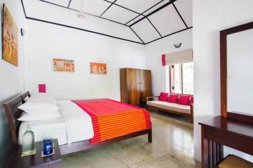 a bedroom with a bed and a couch at Rosyth Estate House in Pinnawala