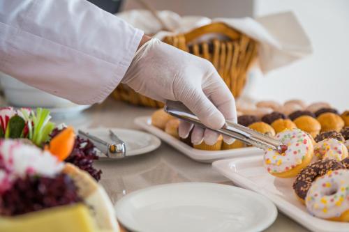 a person in gloves holding tongs over a table of donuts at Sun Hall Hotel in Larnaka