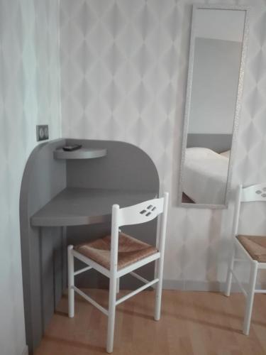 a table and chair in a room with a mirror at Beaune Hôtel in Beaune
