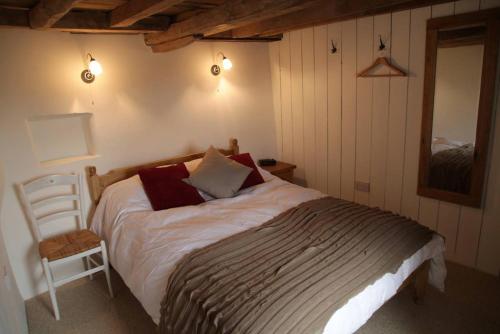 een slaapkamer met een bed, een stoel en een spiegel bij Hope Cottage in Stroud