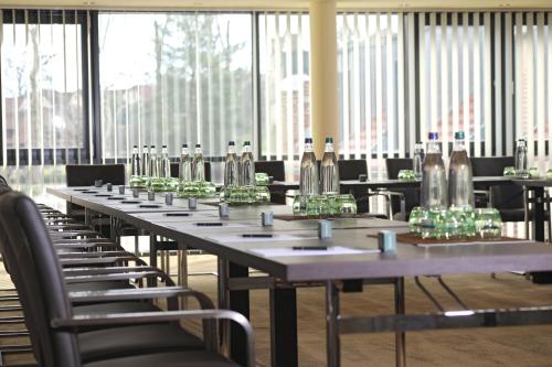 a long table with chairs in a room with windows at Farmer Hotel Basedow in Basedow