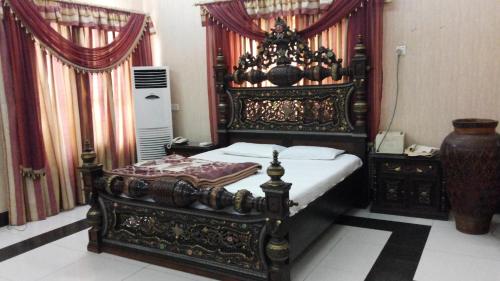 - une chambre avec un lit orné et un cadre en bois dans l'établissement Holiday Inn Guest House, à Kalar Goth