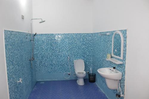 Baño de azulejos azules con aseo y lavamanos en De Perla Resort, en Arugam Bay