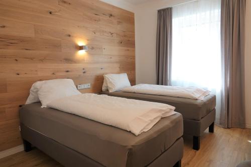 two beds in a room with a wooden wall at Gasthof "Zur Kanne" in Sankt Florian bei Linz