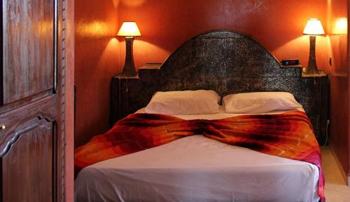a bed in a bedroom with two lamps on the wall at Palais Dar Ouladna in Marrakech