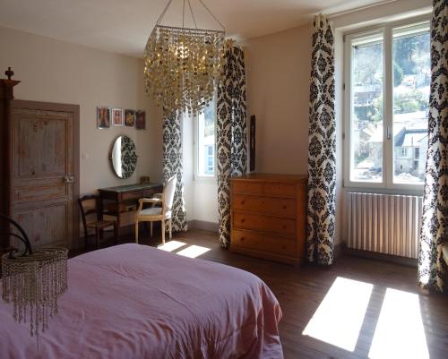 une chambre avec un lit et un lustre dans l'établissement Les Trois Hiboux, à Crespin