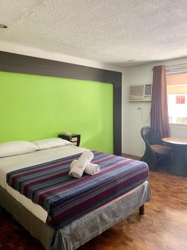 a bedroom with a bed with a green wall at Maharajah Hotel in Angeles